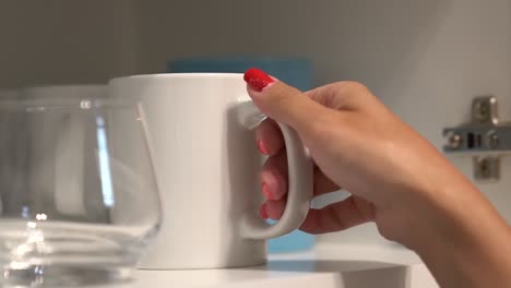 woman taking out a white cup to make tea or coffee in the morning