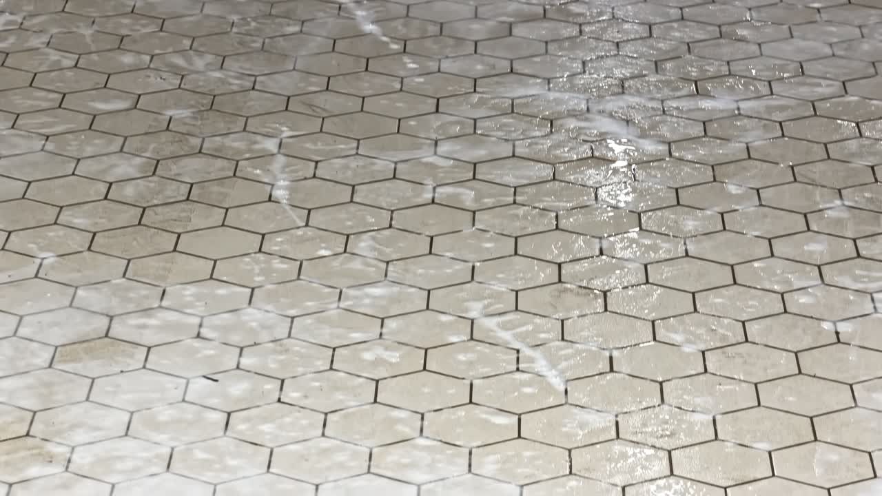 Soapy tiled floor being cleaned with mop bucket during sanitation