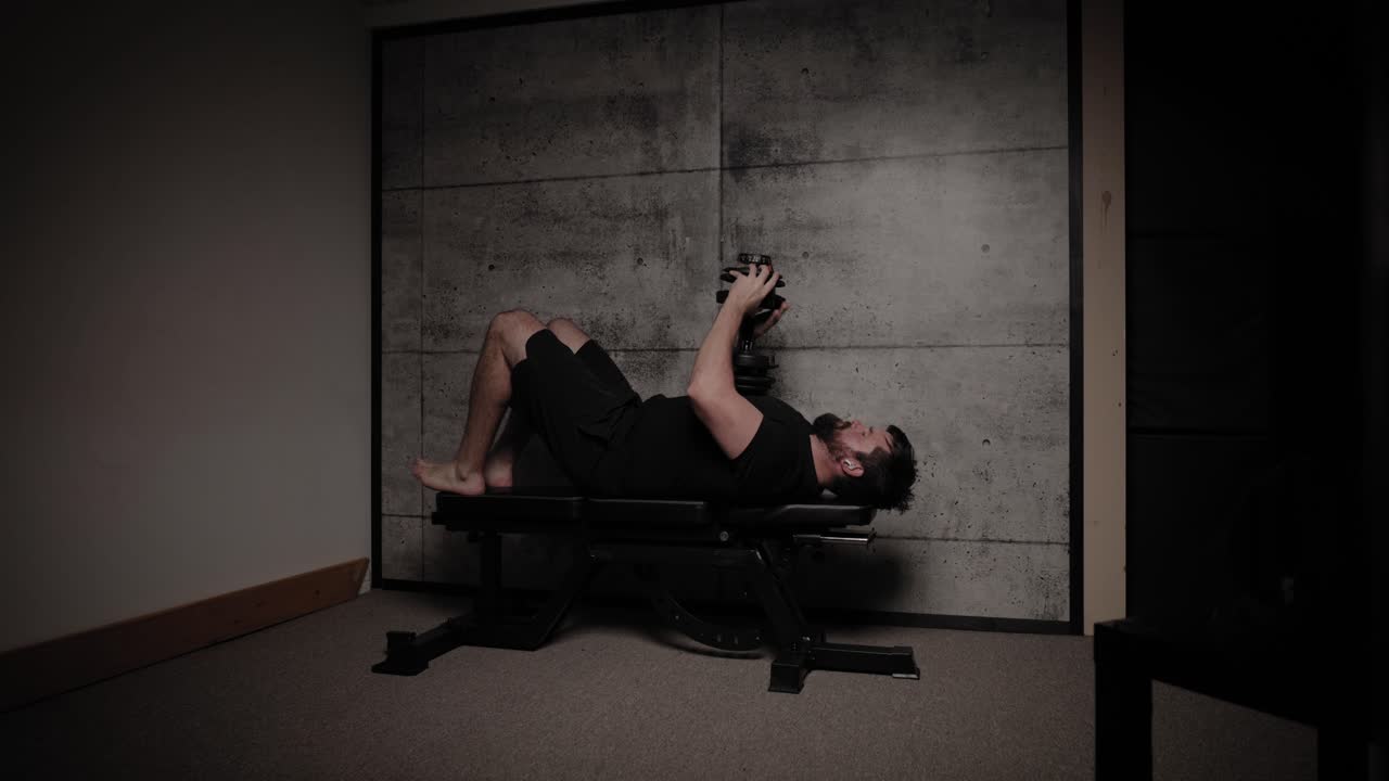 extensión de tríceps, iluminación cinematográfica, hombre blanco vestido con ropa de gimnasio negra