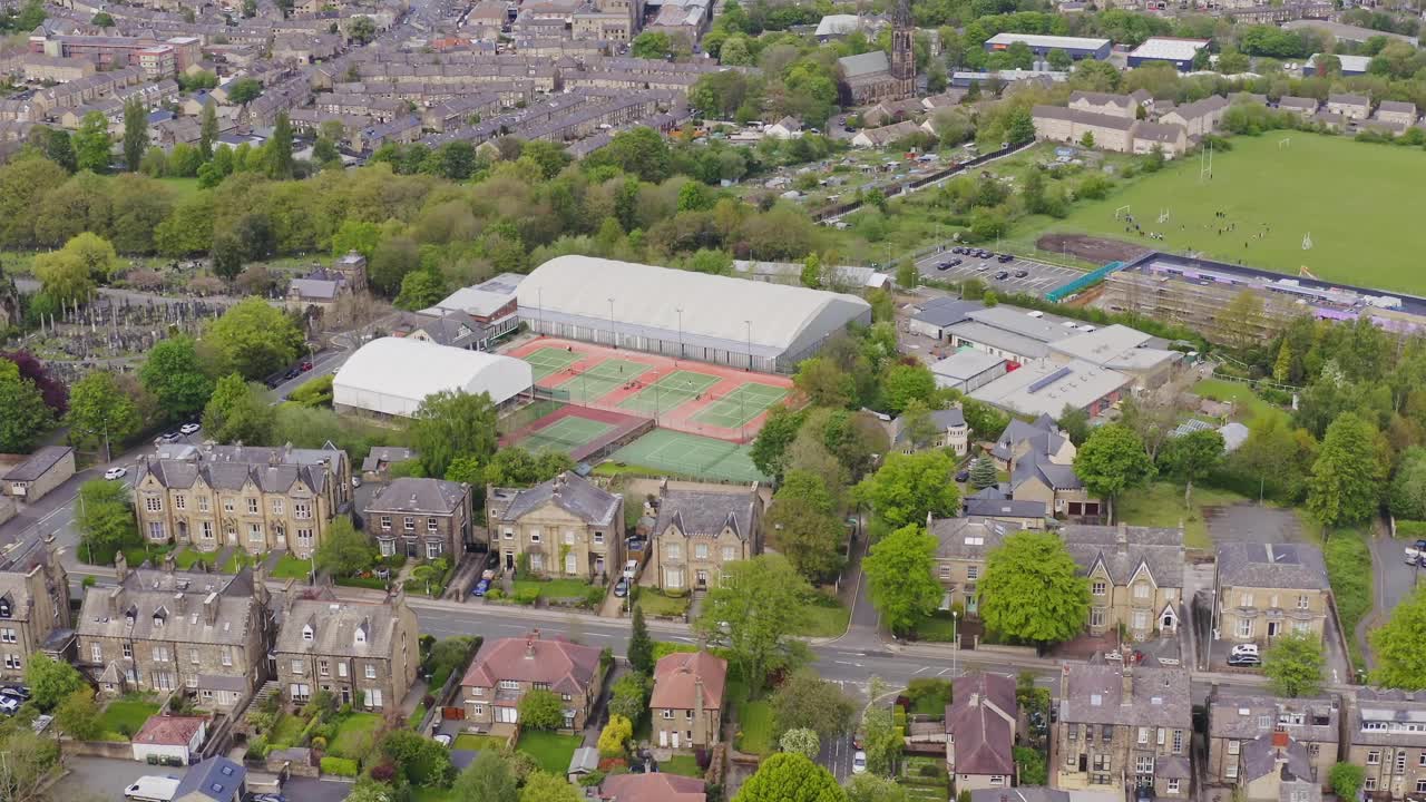 Aerial drone flyover shot of a tennis club and courts in English housing estate