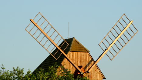 view of a wooden historic mill and its blades standing among the apple trees