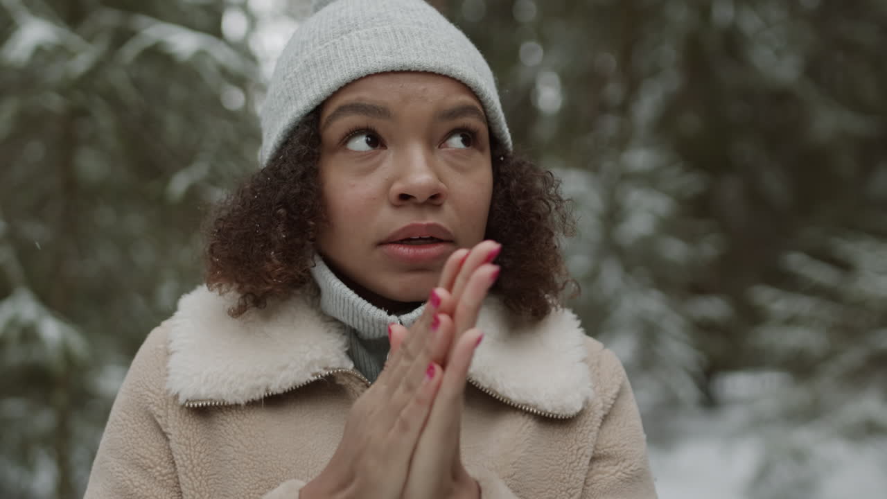 Woman warming hands in a snowy forest