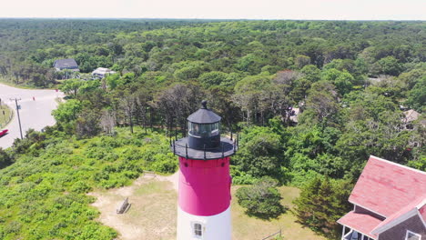 Aerial-Drone-Shot-Circling-Red-and-White-Light-House-in-Cape-Cod-Massachusetts-with-Beach,-Ocean,-People,-Road-and-Parking-Lot-in-the-Background