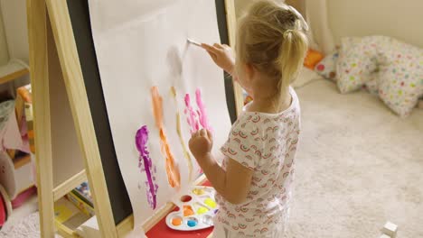 Little-girl-standing-painting-at-an-easel