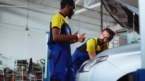 technicians working together to fix car