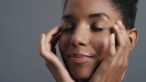 Primer-Plano-Retrato-Hermosa-Mujer-Afroamericana-Tocando-Suavemente-La-Cara-Con-Las-Manos-Disfrutando-De-Una-Tez-De-Piel-Suave-Y-Saludable-Concepto-De-Cuidado-De-La-Piel-De-Belleza-Femenina-Natural