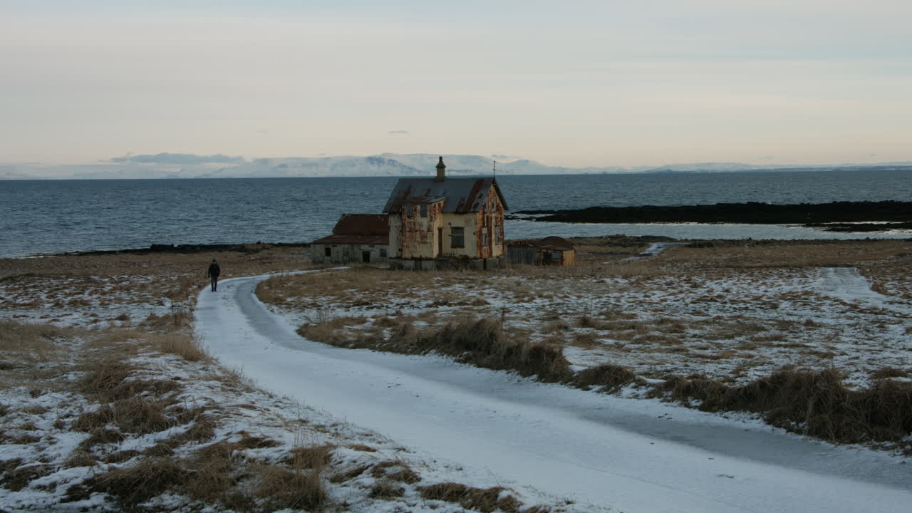 Man stroll on snow-dusted countryside road, calm winter scenery of Icelandic farmhouse - 4k