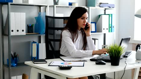 businesswoman talking on smartphone and working in modern office