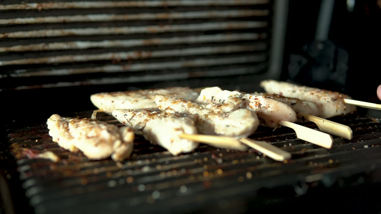 close-up Turn pieces of grilled meat on a grill grill grill, seasoned chicken meat stuffed on a wooden stick, slow motion