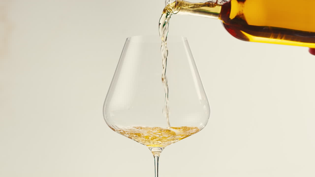 Orange or white wine bottle and glass against a sunset in a peaceful vineyard, pouring of ecological natural wine.