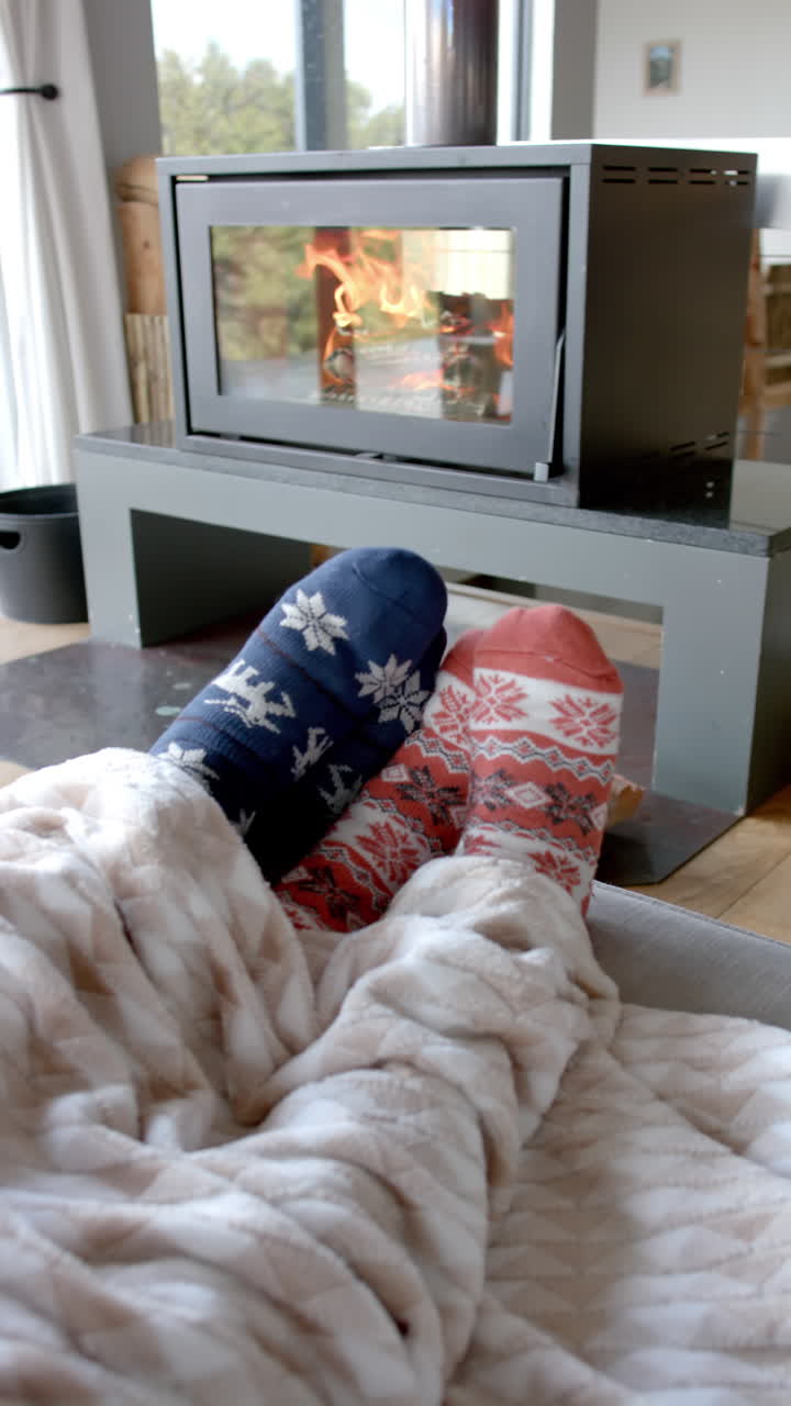Slow-motion vertical video shows biracial couple's feet by fireplace at home