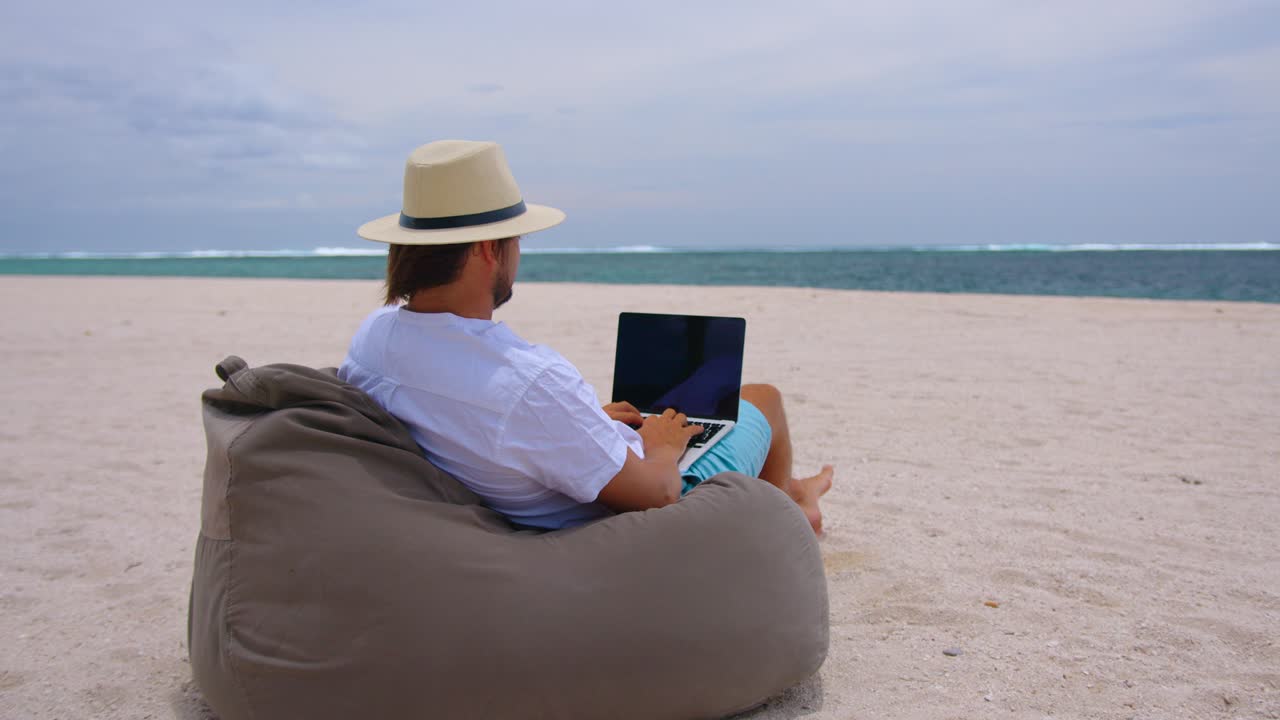 trabajo independiente, viajes y vacaciones concepto. un hombre con sombrero amarillo sentado en la playa fondo del océano. trabajo mientras está de vacaciones en el mar