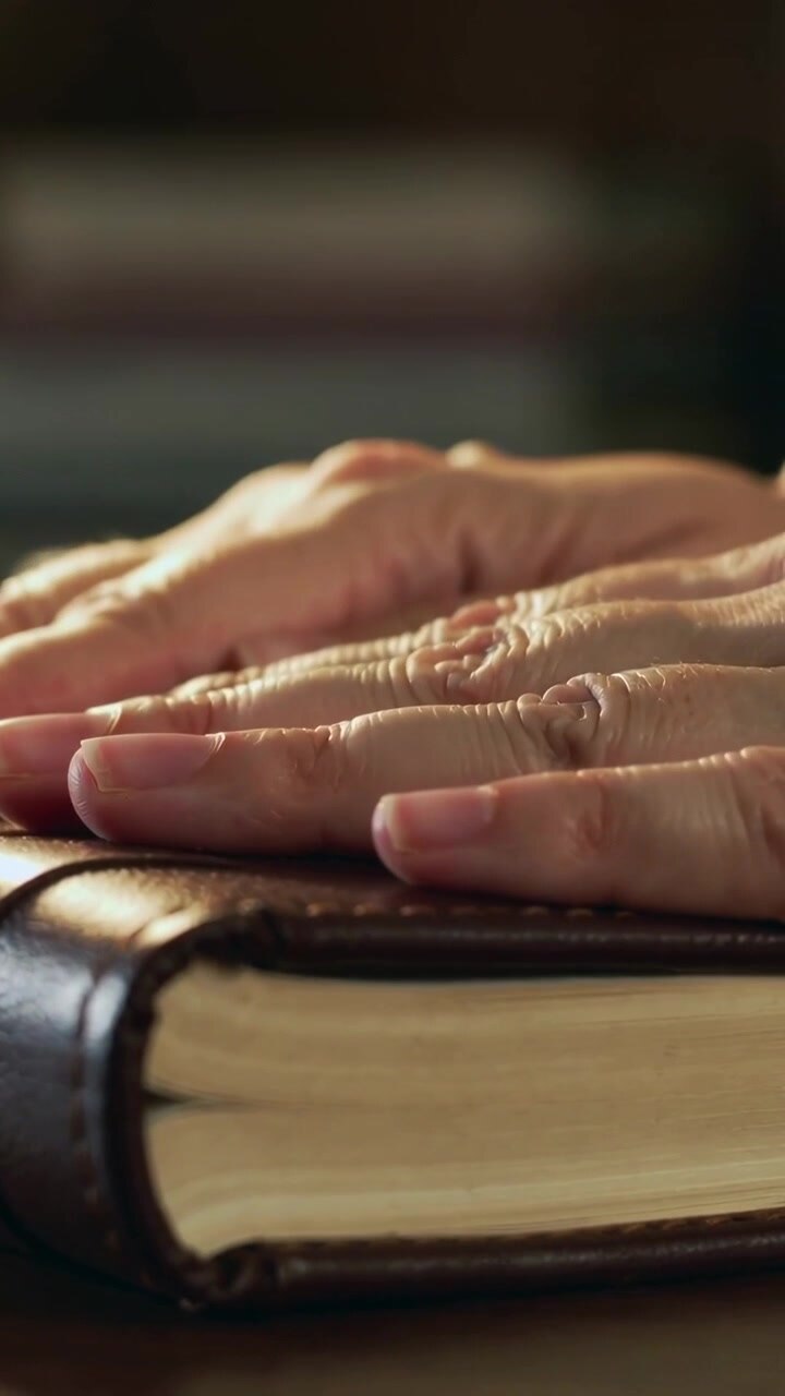 Vertical video: Hand entering, urging both hands pressing leather journal on desk, feeling stitch