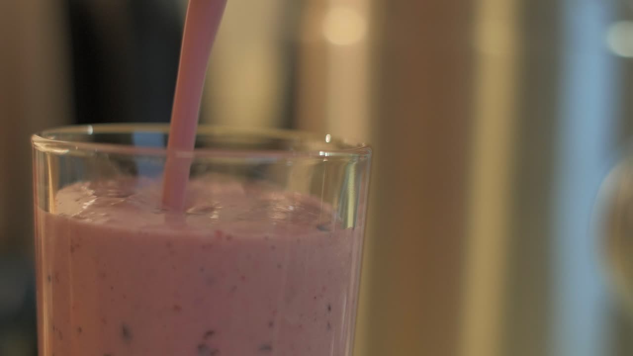 Healthy berry and banana cocktail poured into glass, close up shot