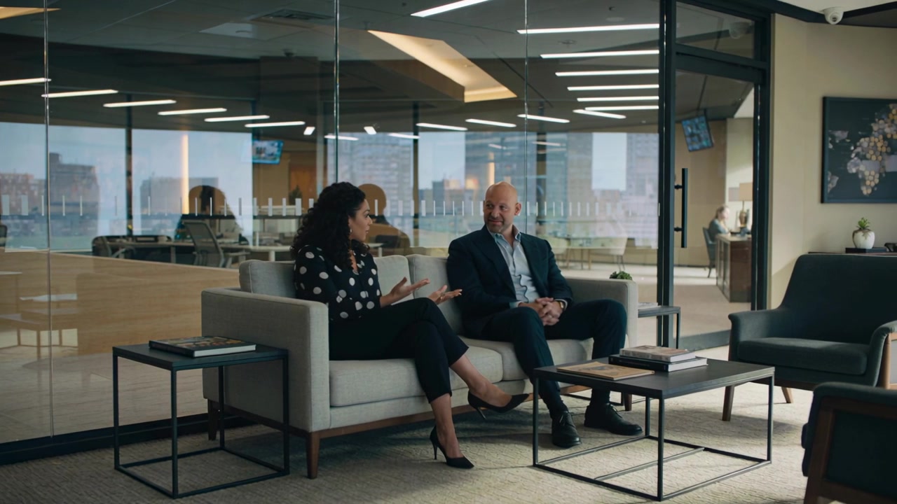 Talking woman starting project on sofa in office, gesturing while man listening, business attire