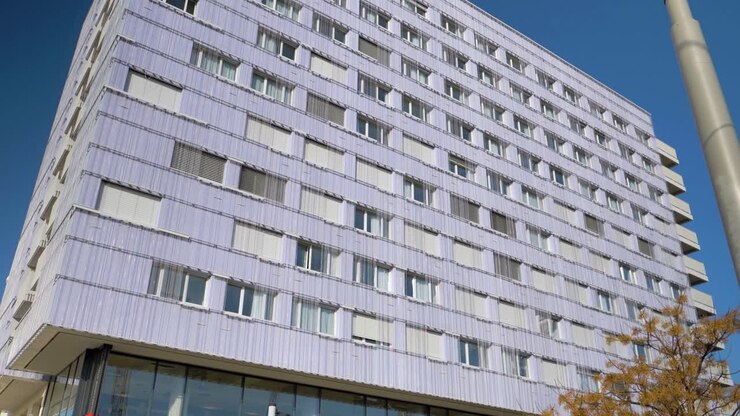 Prospettiva ascendente: edificio inclinato con decorazioni a catena, lampioni illuminati in primo piano