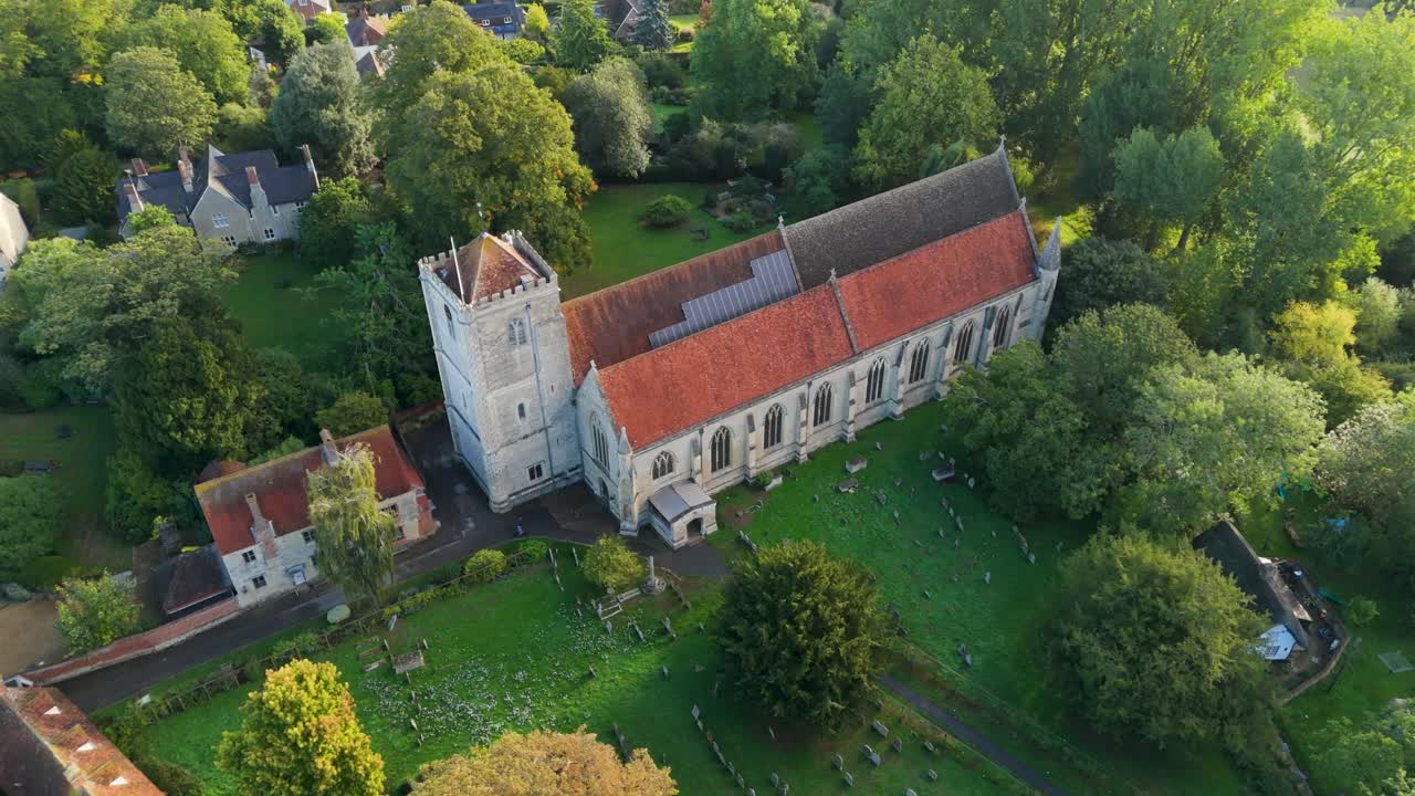 Aerial drone orbit of Dorchester Abbey in Oxfordshire, England. Shot in the morning light, the drone circles clockwise from the abbey frontage across 270°, showing the graveyard and village landscape