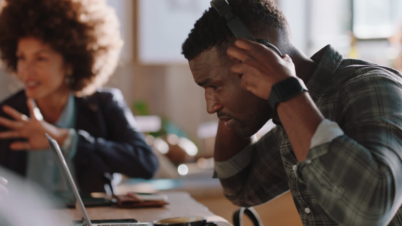 young african american man using laptop in cafe browsing online checking email messages listening to music working in coffee shop