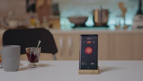 smart home application on phone placed on kitchen desk in empty house