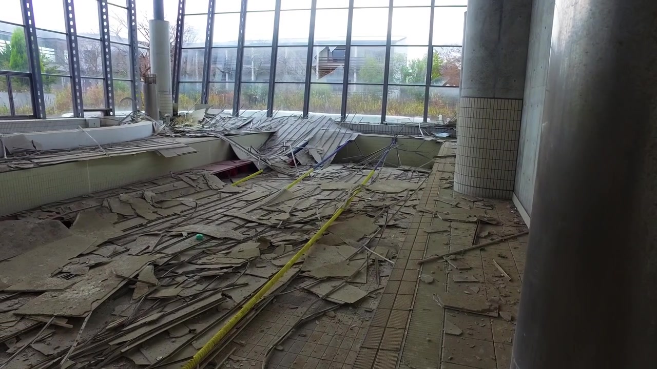 Panorámica melancólica a través de un centro acuático en ruinas lleno de escombros.