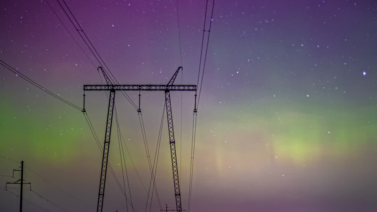 Northern lights timelapse, purple aurora hues with green shade between high voltage wire