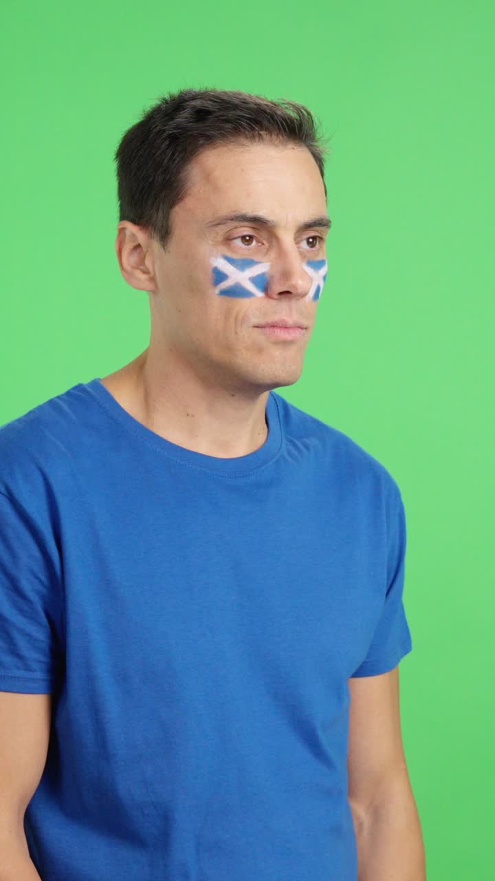 Happy man with scottish flag painted on face looking away