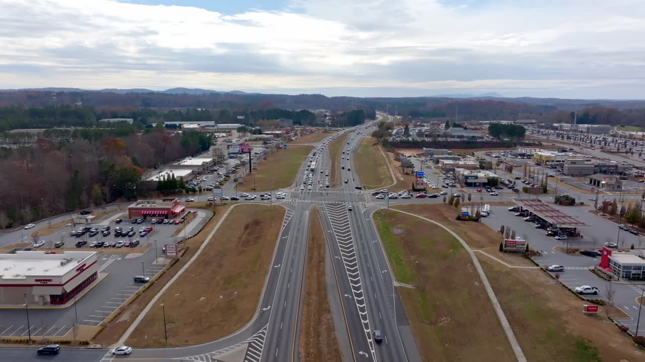 vista aérea de una intersección de autopista con negocios circundantes y estacionamientos en un día nublado