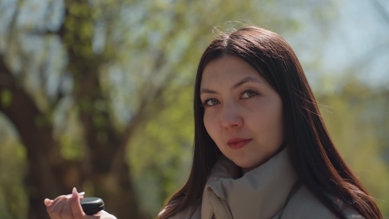 부드러운 햇빛이 비치는 여성의 초상화. 여인은 잎이 무성한 도시 공원 분위기 속에서 자신감 있게 자신의 모습을 비춰보고 있습니다. 자연 공원 환경 속에서 자신감 있게 자신의 모습을 확인하는 여성의 클로즈업