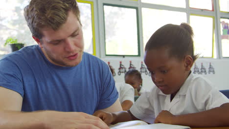 Volunteer-teacher-helping-schoolgirl-at-her-desk,-close-up