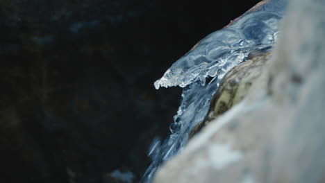 water get out of an icicle in a frozen river in winter, close up, slow motion