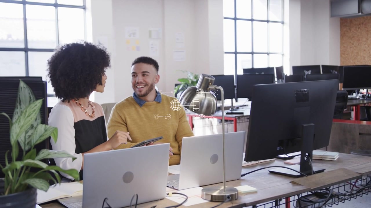 Woman tapping tablet and initiating joint tech review, man leaning, animated icons marking monitor