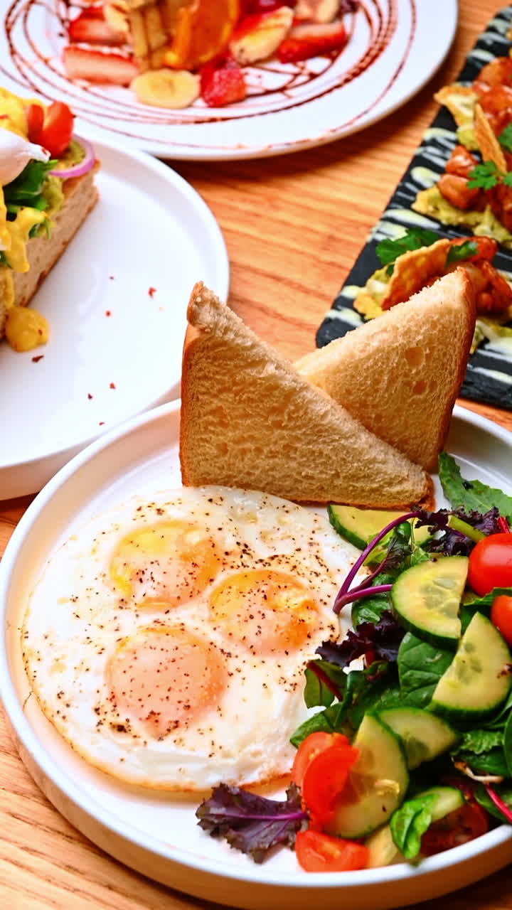 Assorted brunch dishes on wooden table. Eggs, salad, avocado toast, shrimp bites and dessert served together for generous brunch
