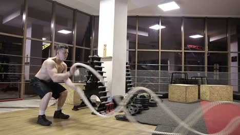 session battle ropes. an athlete who develops a gym in a functional training, performs a crossfit exercise with combat ropes, a wheel-strike that fights with ropes