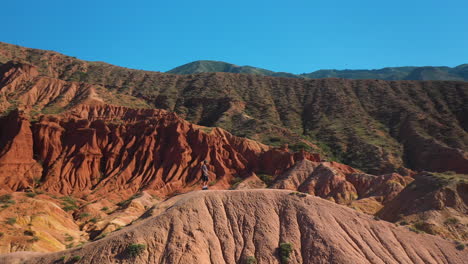 hombre de pie en la cresta del cañón en el cañón de cuento de hadas cerca del lago issyk-kul en karakol, kirguistán, tiro de dron giratorio