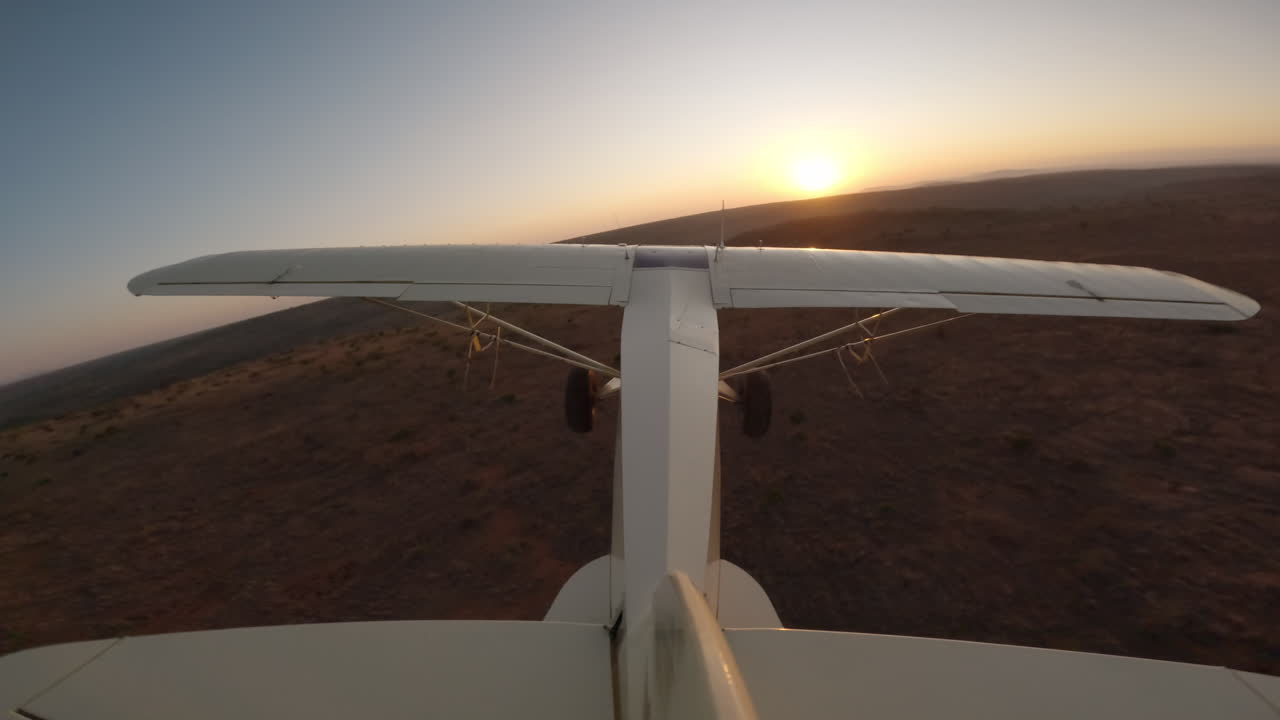 Piccolo aereo in volo sopra le pianure al tramonto