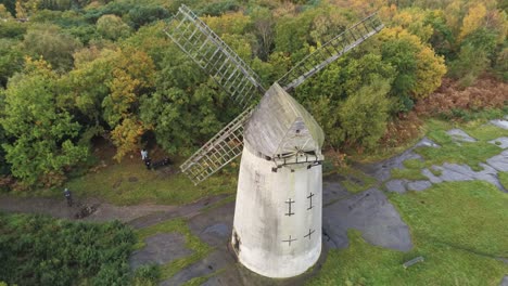 traditional wooden stone flour mill windmill preserved in autumn woodland aerial view countryside birdseye pull back reveal