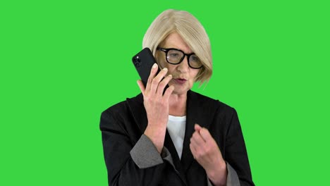mujer mayor de edad seria hablando por teléfono en una pantalla verde, llave de croma