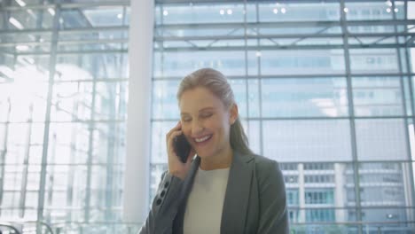 Businesswoman-talking-on-mobile-phone-in-the-lobby-at-office-4k