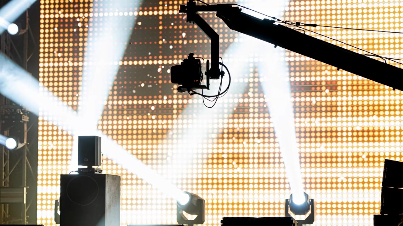 Inquadrature iniziali che mostrano una testa di telecamera remota che regola la panoramica o l'inclinazione sul palco per le prove, LED ambra.