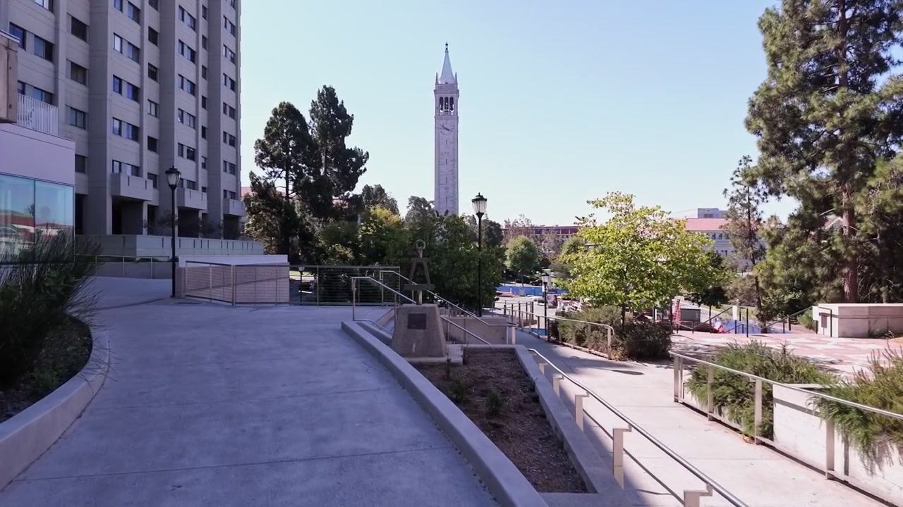 Paseo dinámico por el campus de UC Berkeley que muestra la icónica Torre Sather, dormitorios modernos, senderos soleados, árboles frondosos y arquitectura universitaria clásica bajo la brillante luz natural del mediodía