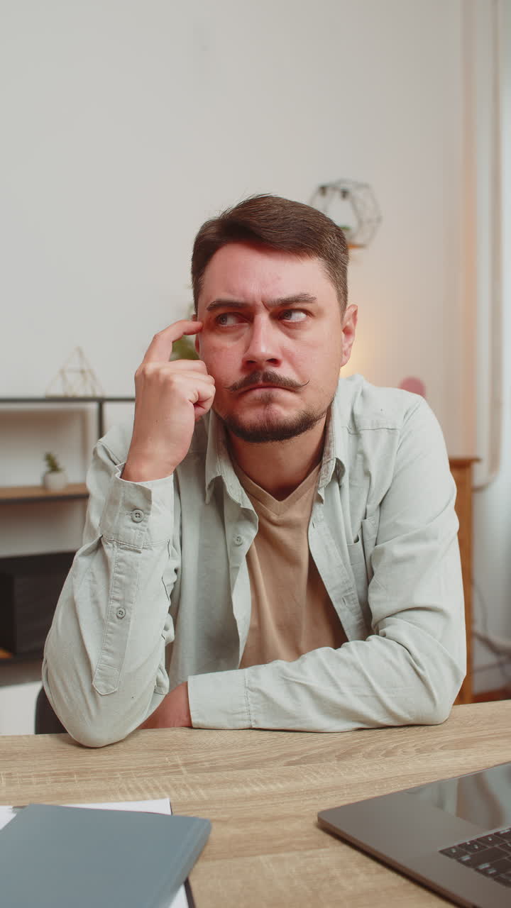 Caucasian smart focused young man freelancer pensive thoughtful sitting at home office table
