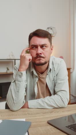 caucasian smart focused young man freelancer pensive thoughtful sitting at home office table