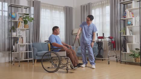 full body side view of asian male nurse talking about medical test results and encouraging a patient crying in the wheelchair after physical therapy at home