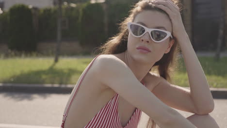 woman in red and white striped swimsuit with sunglasses