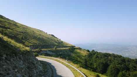 aerial establishing over narrow mountain roads below mountain peaks at sunrise