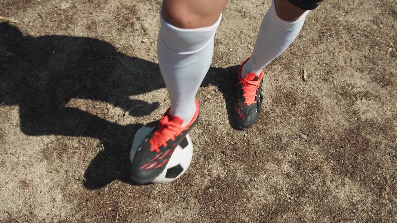 Pernas e pés do jogador de futebol com a bola