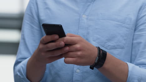 asisstant holding smartphone texting colleagues on break. male hands closeup.