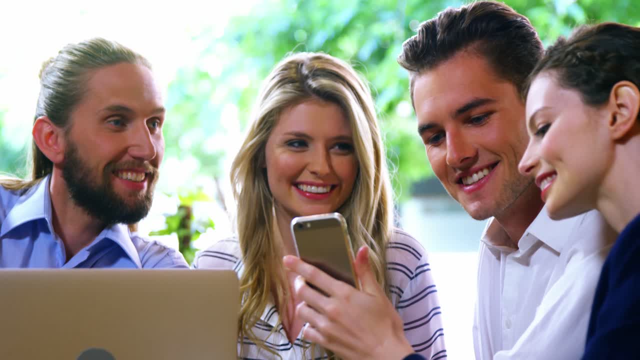 amigos felices usando computadoras portátiles y teléfonos móviles