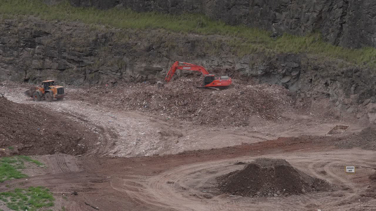 Bulldozer and digger working moving wood chip and recycling in large pit