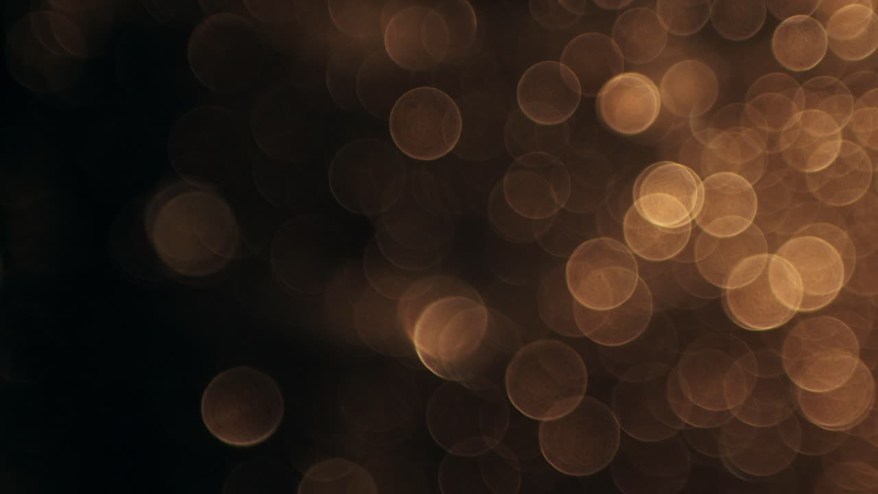Luci bokeh dorate astratte che svaniscono su sfondo scuro